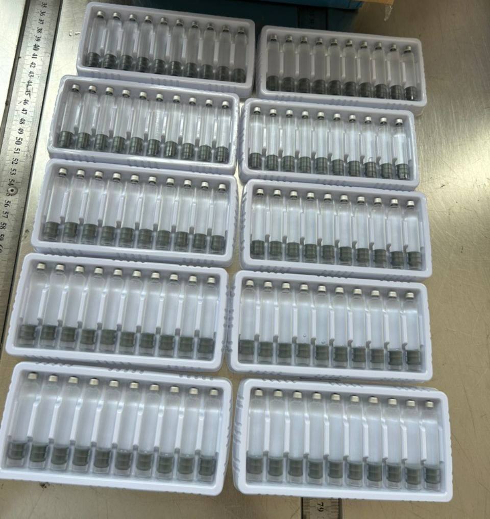 Vials arranged in white packing trays at a workbench